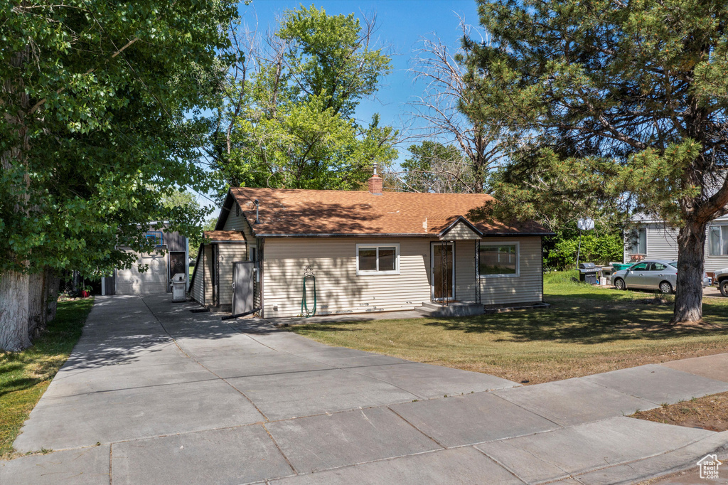 View of front facade with driveway, a front yard, and a chimney