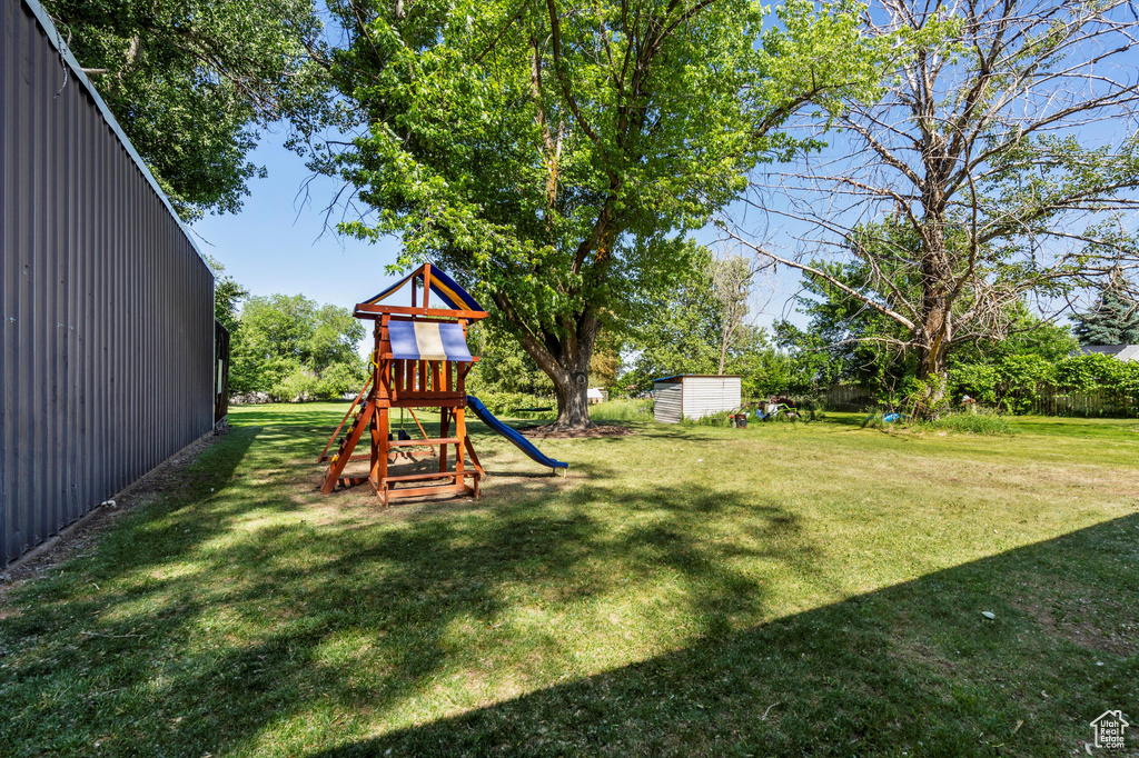 View of grassy yard featuring a playground and an outdoor structure