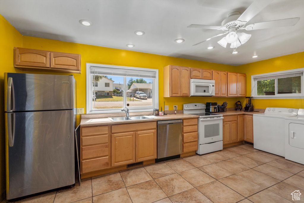 Kitchen featuring stainless steel appliances, washing machine and clothes dryer, a sink, light countertops, and light tile patterned floors