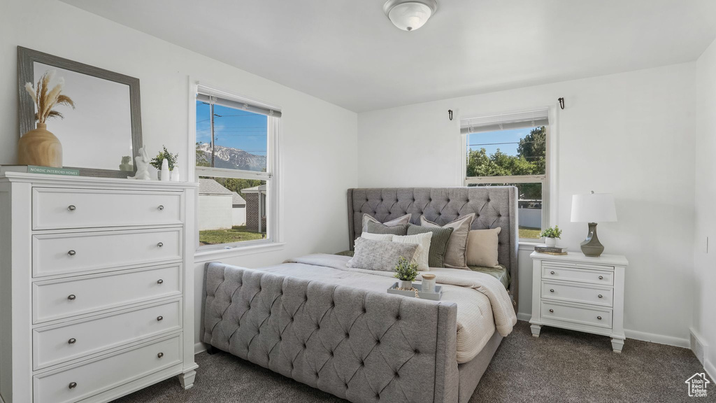 Bedroom with multiple windows, dark carpet, and baseboards
