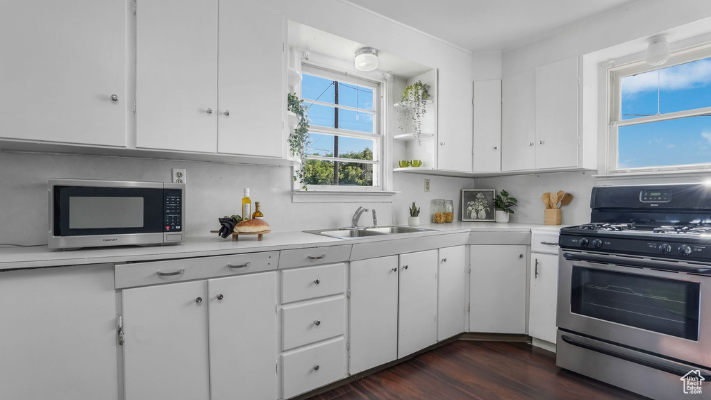 Kitchen with appliances with stainless steel finishes, a sink, light countertops, and white cabinets