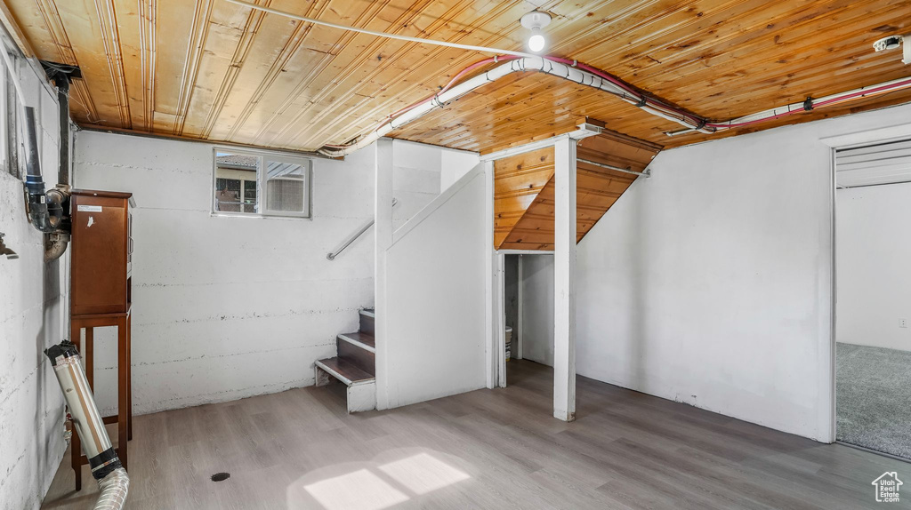 Finished basement with wooden ceiling, wood finished floors, and stairway