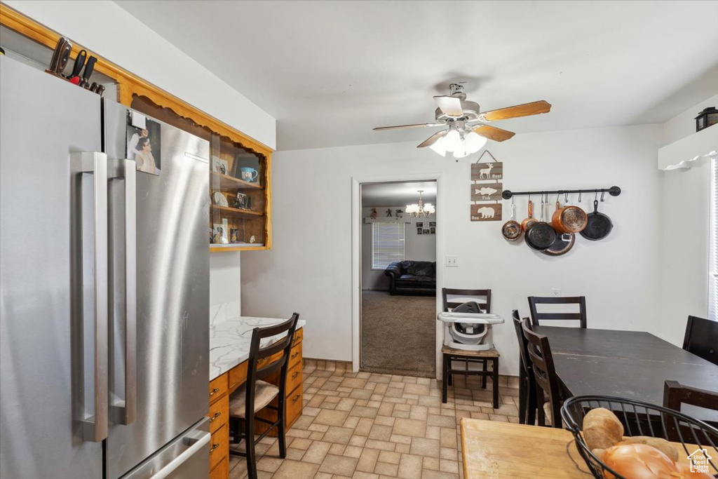 Dining room featuring ceiling fan, brick patterned flooring, and a chandelier