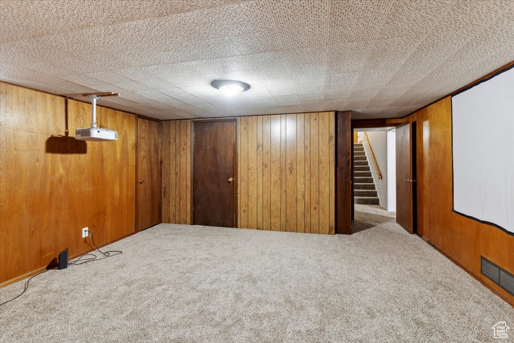 Finished basement with carpet, stairs, and wooden walls