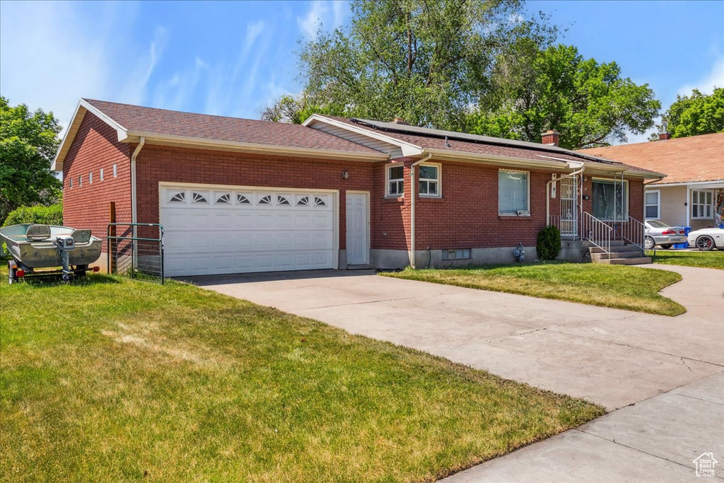 Ranch-style home featuring driveway, brick siding, a garage, and a front lawn