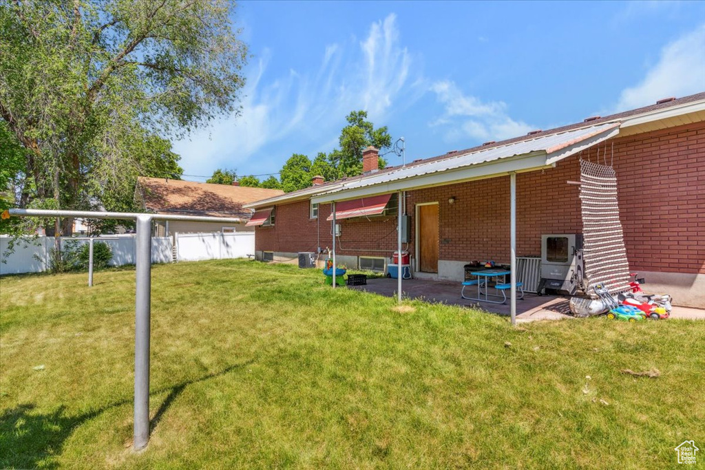 Back of house with a patio, brick siding, and a chimney