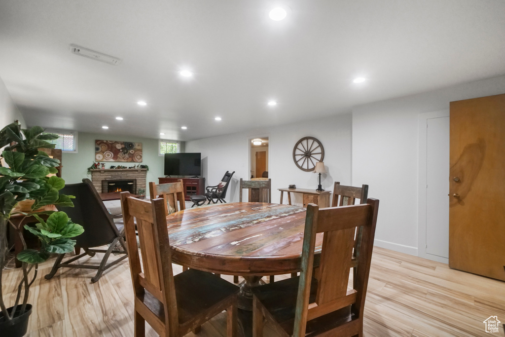 Dining room with a lit fireplace, light wood-style floors, and recessed lighting