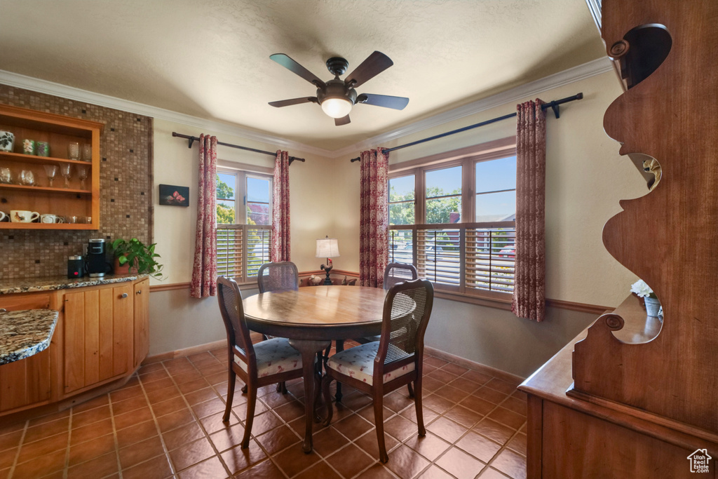 Tiled dining area featuring a ceiling fan, crown molding, and baseboards
