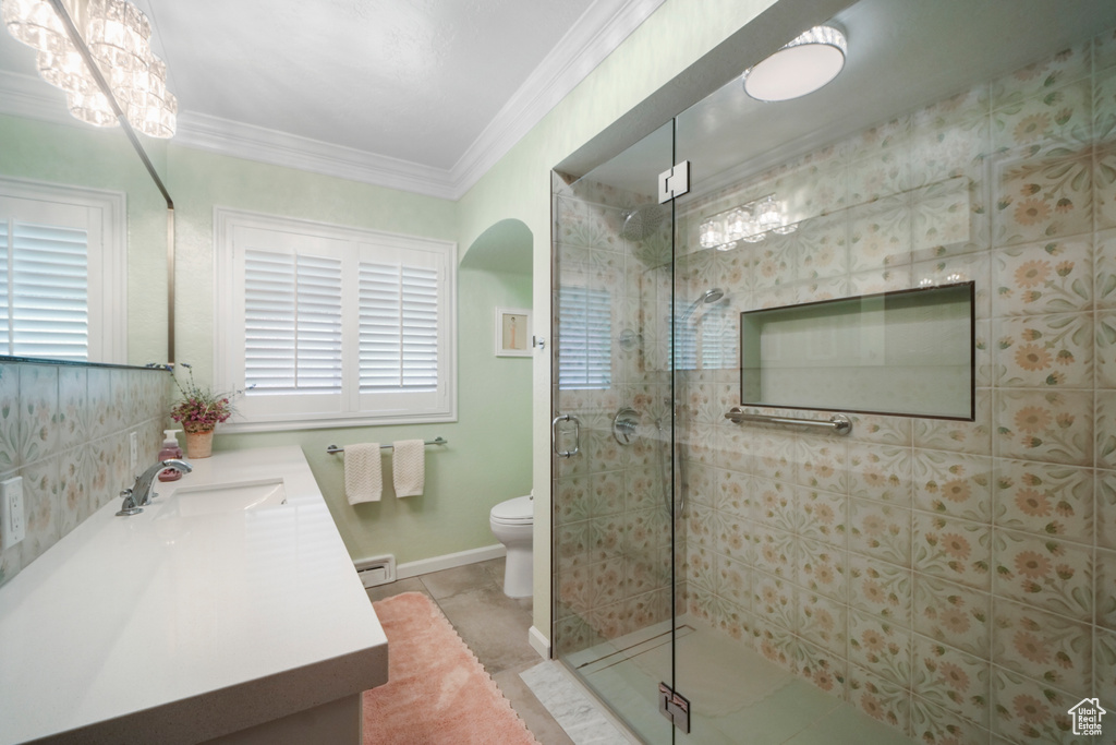 Bathroom featuring vanity, a stall shower, toilet, crown molding, and a baseboard radiator