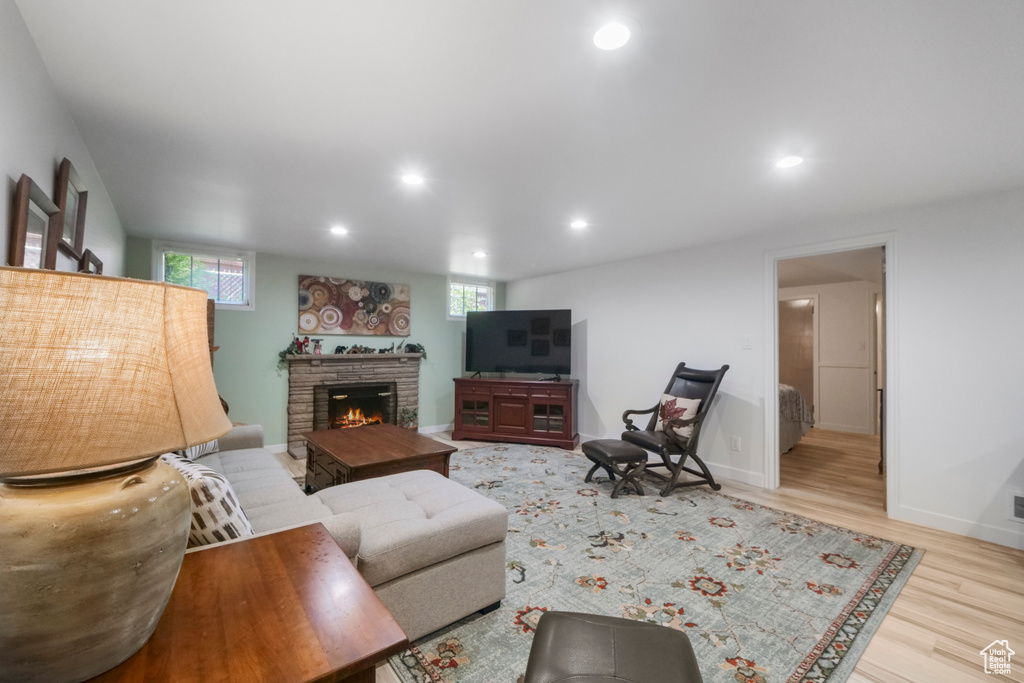 Living room featuring plenty of natural light, wood finished floors, a lit fireplace, recessed lighting, and baseboards