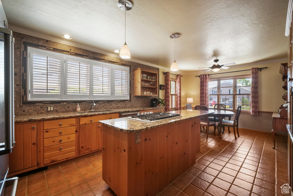 Kitchen featuring a sink, tasteful backsplash, tile patterned floors, ornamental molding, and a ceiling fan