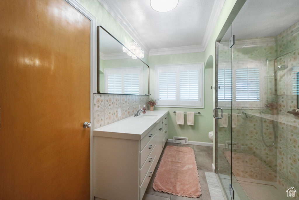 Bathroom with vanity, a shower stall, toilet, crown molding, and tile patterned floors