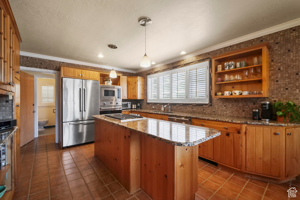 Kitchen featuring appliances with stainless steel finishes, a sink, plenty of natural light, tasteful backsplash, and ornamental molding