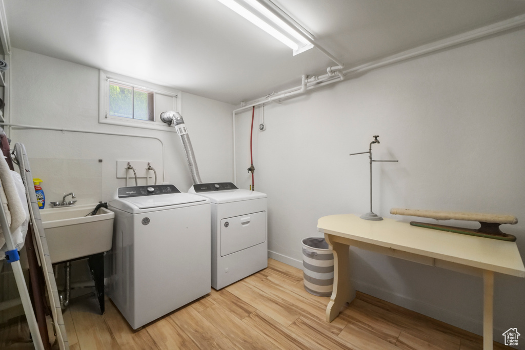 Laundry area with washer and dryer, light wood-type flooring, and a sink