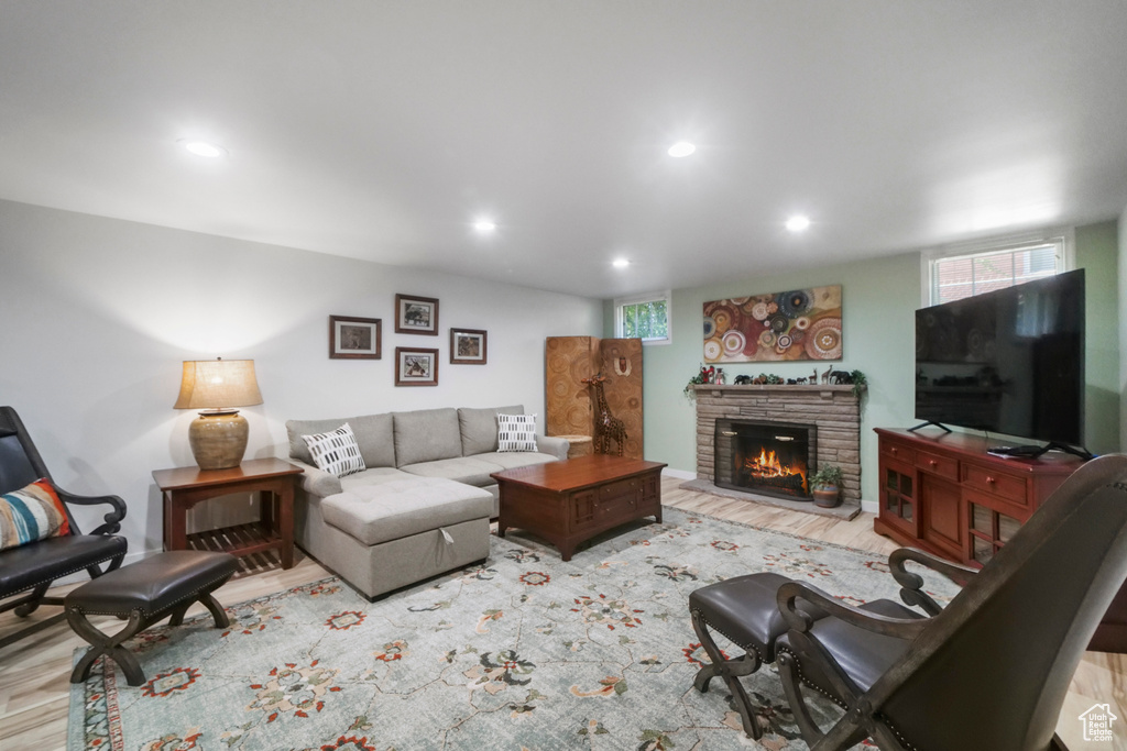 Living room featuring a stone fireplace, recessed lighting, wood finished floors, and plenty of natural light