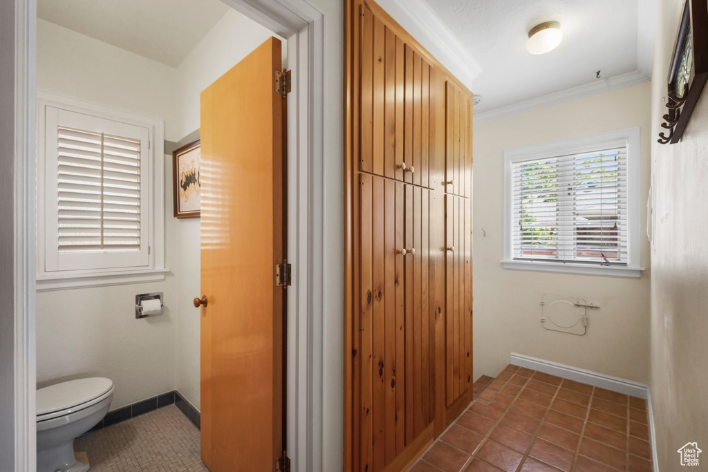 Bathroom with toilet, ornamental molding, tile patterned flooring, and baseboards