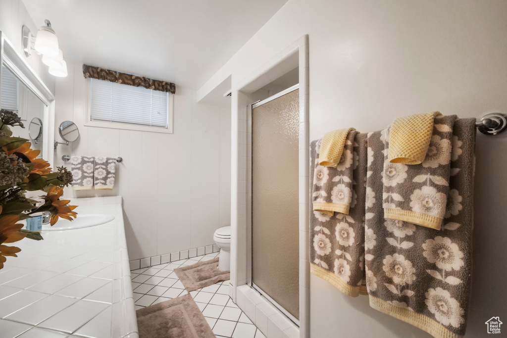 Full bathroom with a stall shower, vanity, tile patterned flooring, and toilet