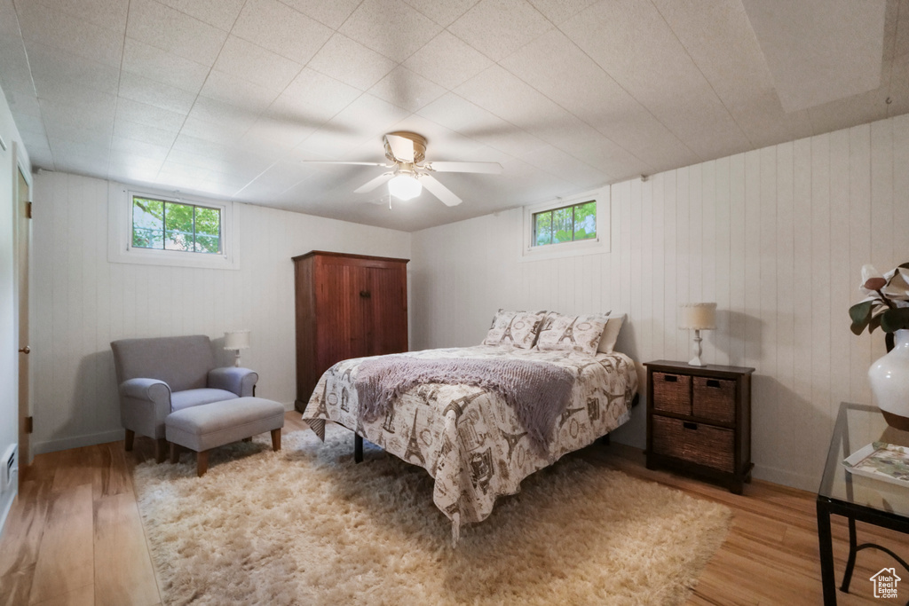 Bedroom with wood finished floors, a ceiling fan, and wood walls