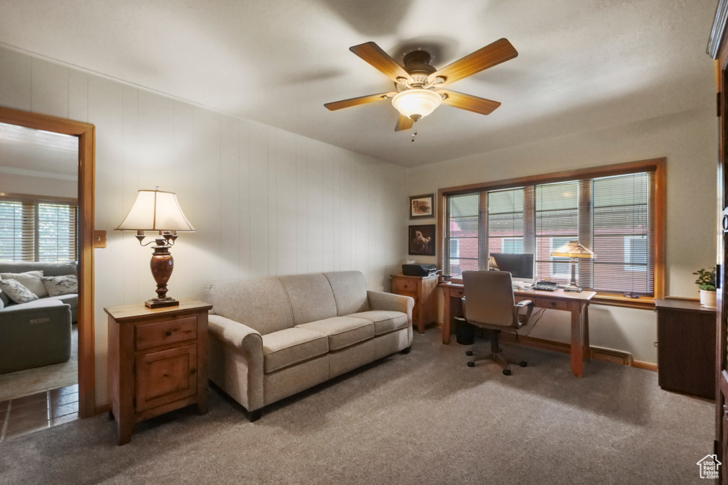 Carpeted home office with plenty of natural light and ceiling fan