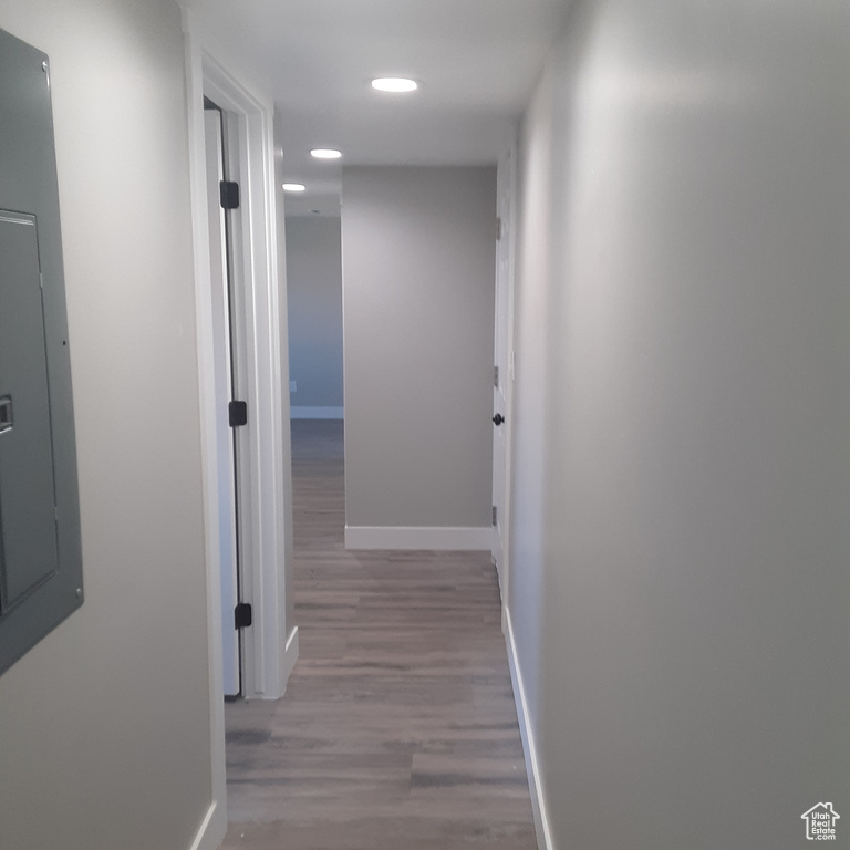 Corridor featuring baseboards, wood finished floors, recessed lighting, and electric panel