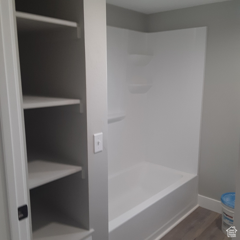 Full bathroom featuring wood finished floors, baseboards, and shower / tub combination