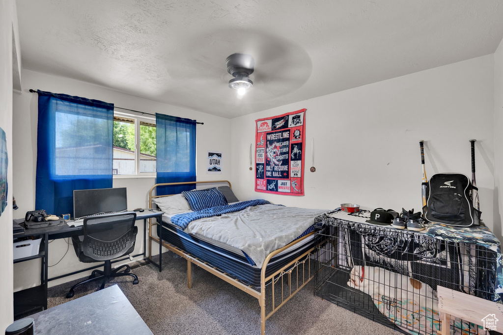 Carpeted bedroom with an office area and a ceiling fan