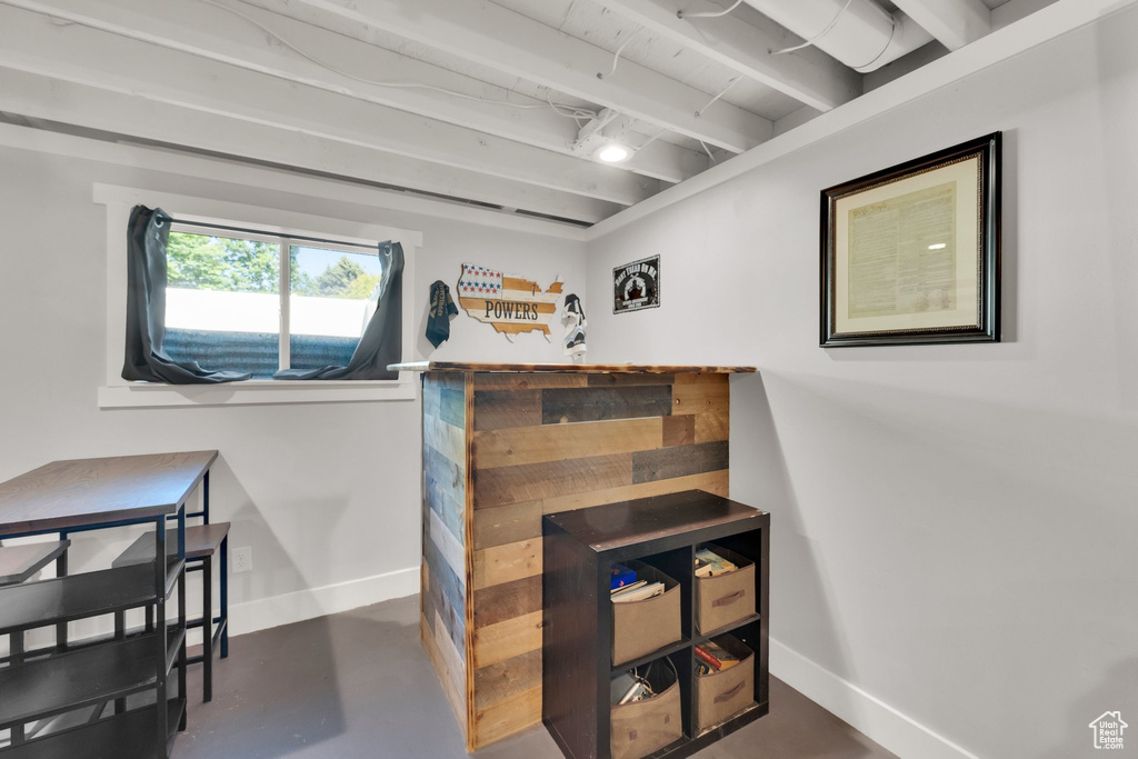 Interior space with baseboards, concrete floors, and beamed ceiling