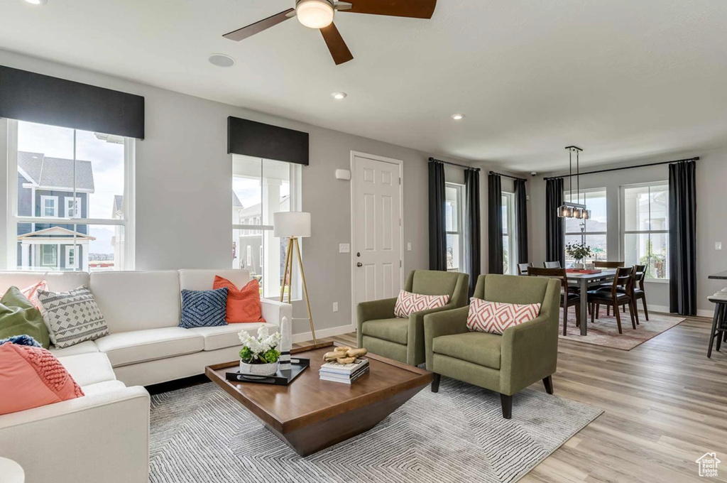 Living area featuring a ceiling fan, light wood-style flooring, recessed lighting, baseboards, and a chandelier