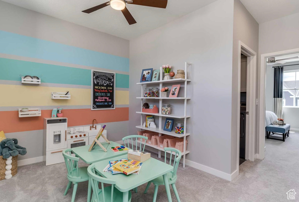 Recreation room featuring light carpet, a ceiling fan, and baseboards
