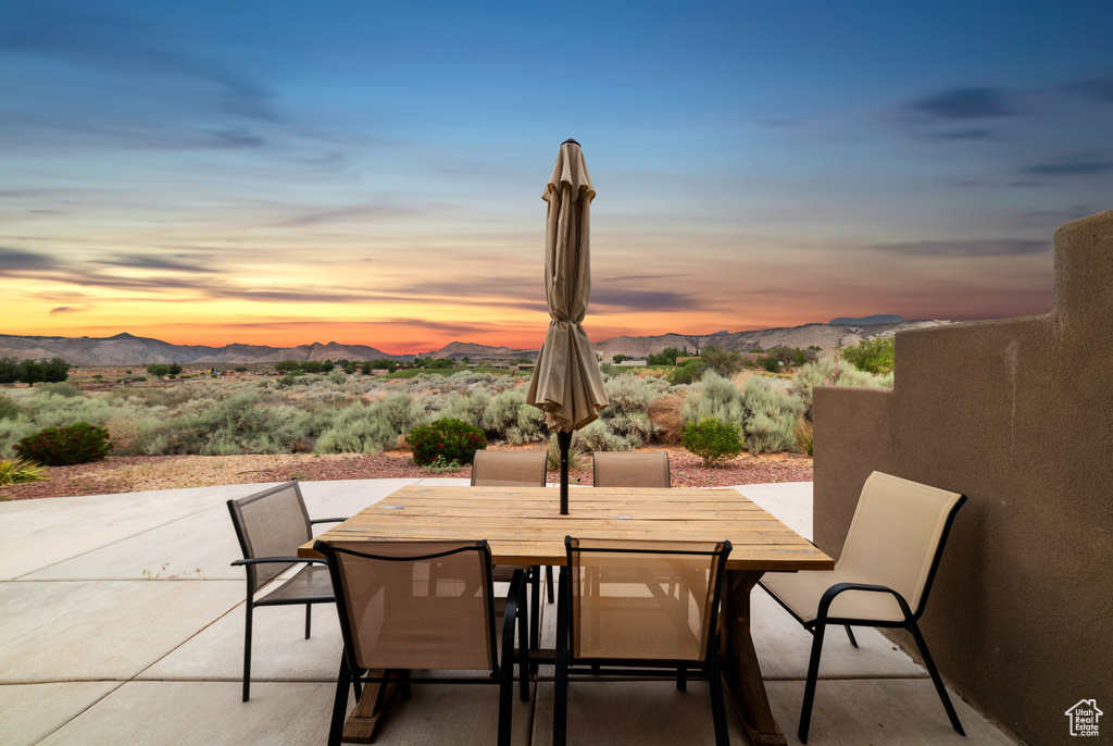 Patio terrace at dusk with a mountain view, outdoor dining space, and a patio