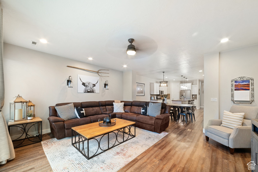 Living room featuring light wood-style floors, ceiling fan, recessed lighting, and baseboards