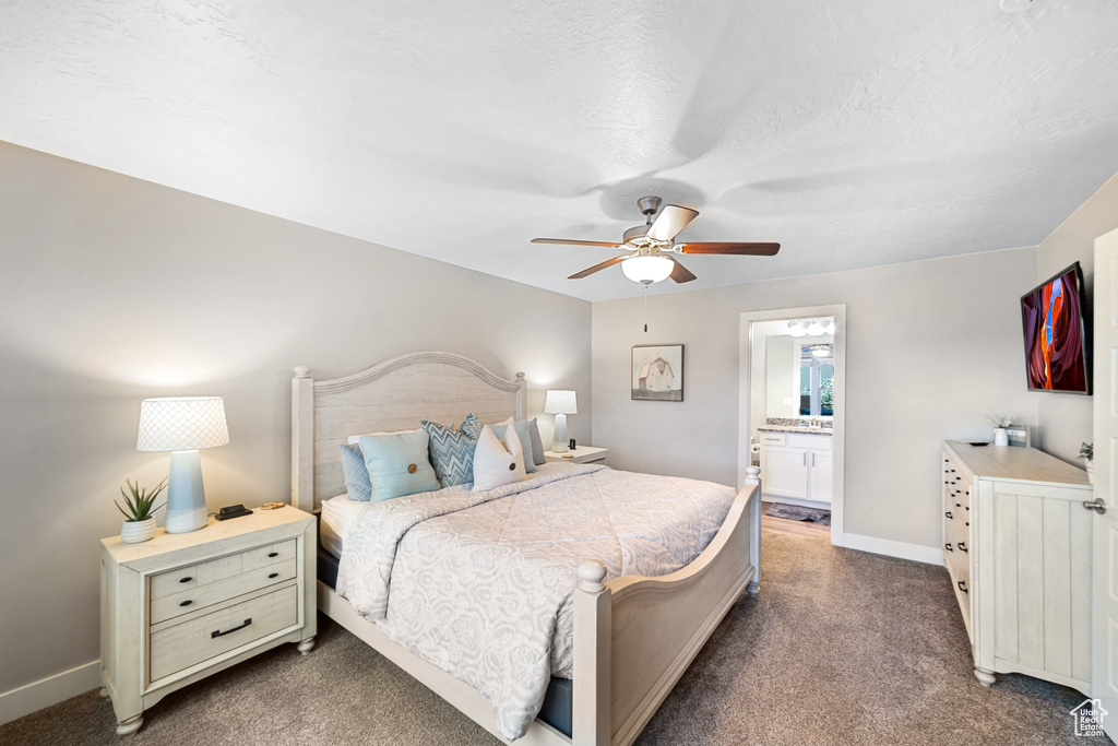 Bedroom with dark carpet, baseboards, ceiling fan, and ensuite bathroom