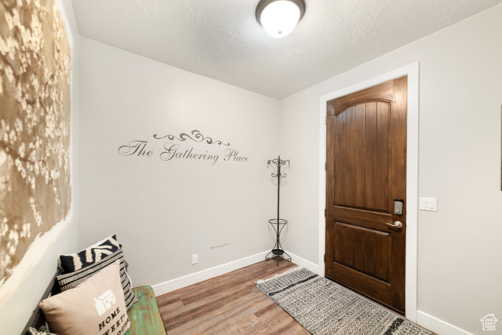 Foyer with baseboards, wood finished floors, and a textured ceiling