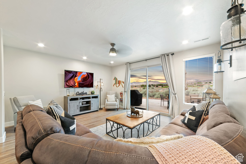 Living room with light wood-style flooring, a ceiling fan, recessed lighting, and baseboards