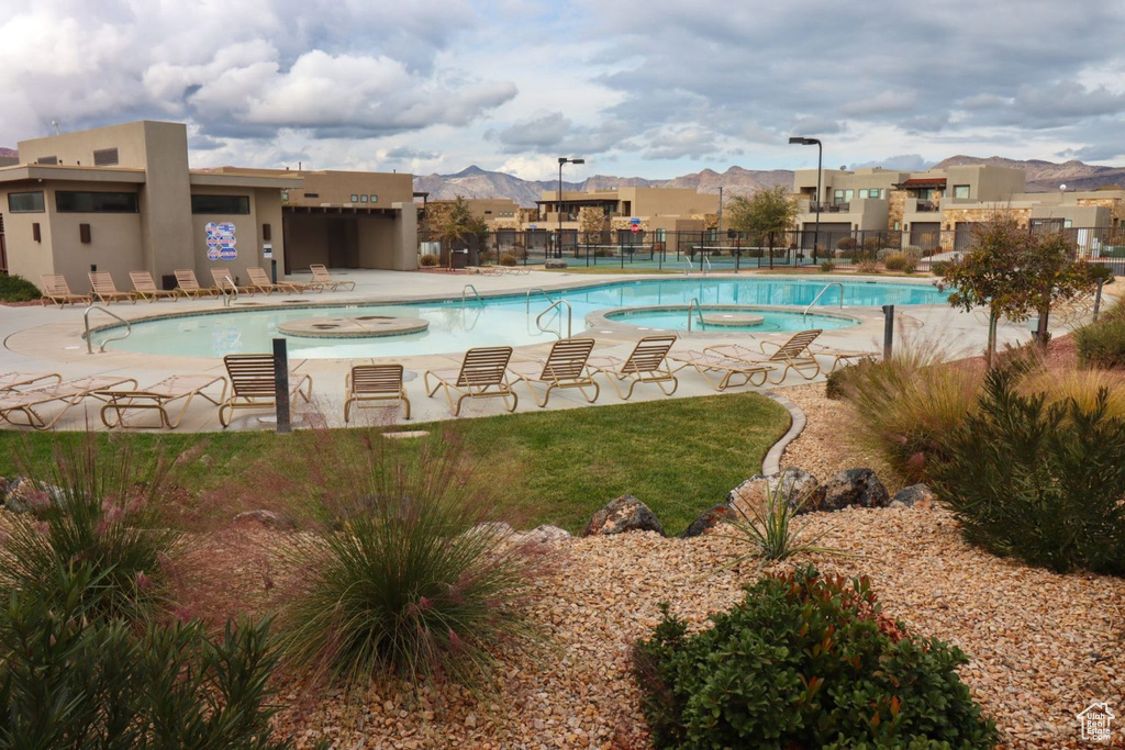Community pool featuring a hot tub, a residential view, a patio area, and a mountain view