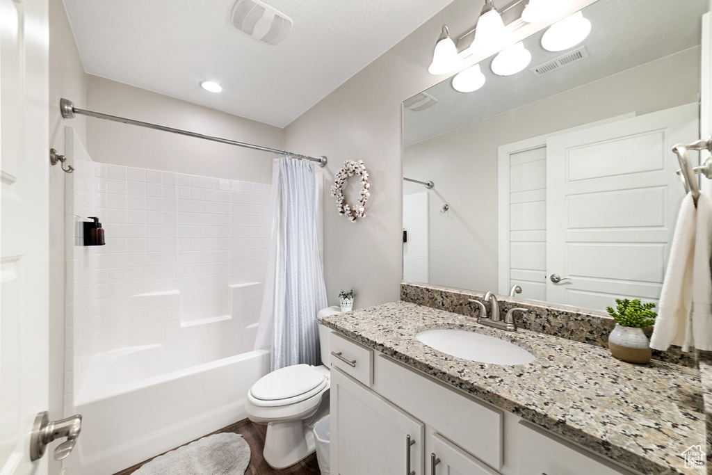 Bathroom featuring shower / bathtub combination with curtain, toilet, vanity, and wood finished floors