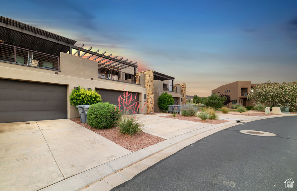 Contemporary house featuring stucco siding, concrete driveway, an attached garage, and a balcony