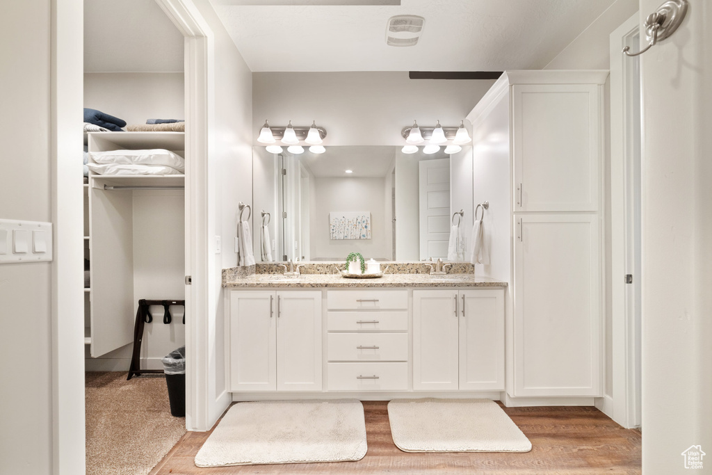 Bathroom with double vanity, wood finished floors, and a closet