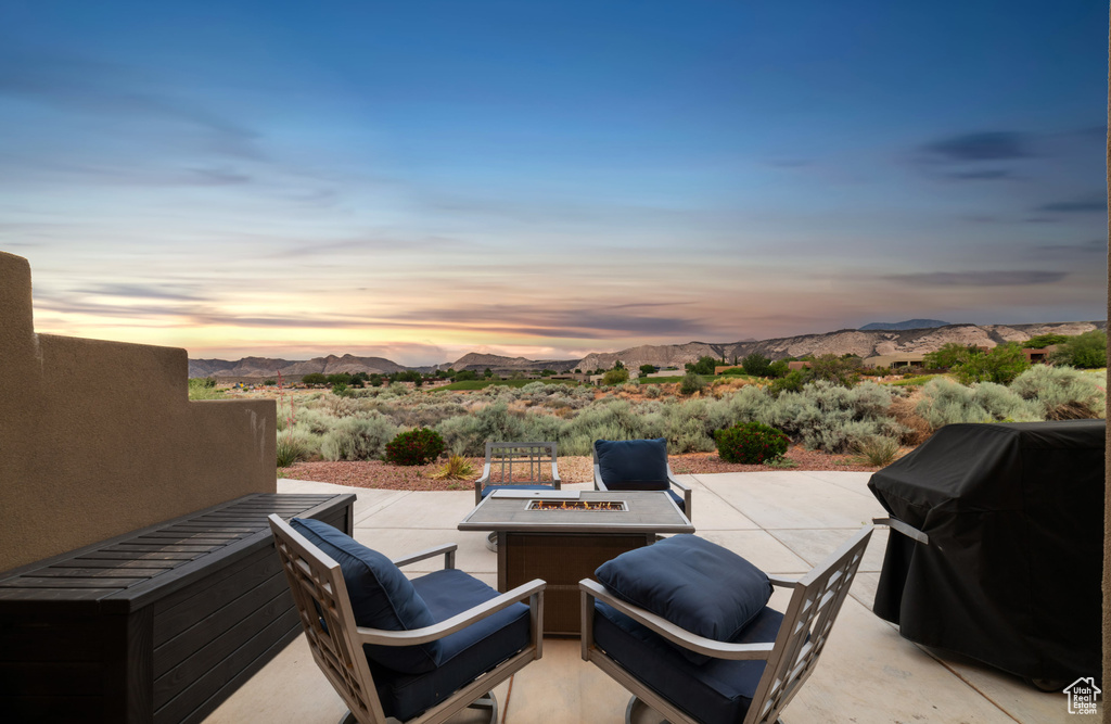 Patio terrace at dusk with a patio, a mountain view, a grill, and a fire pit