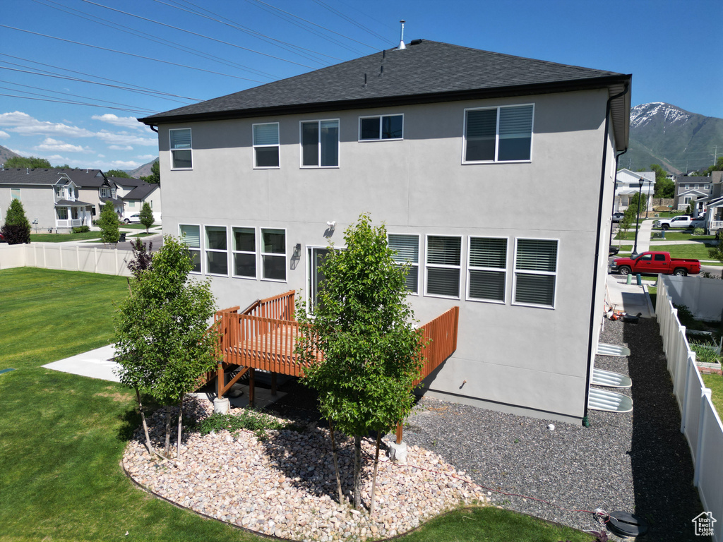 Back of house featuring a wooden deck, stucco siding, and roof with shingles