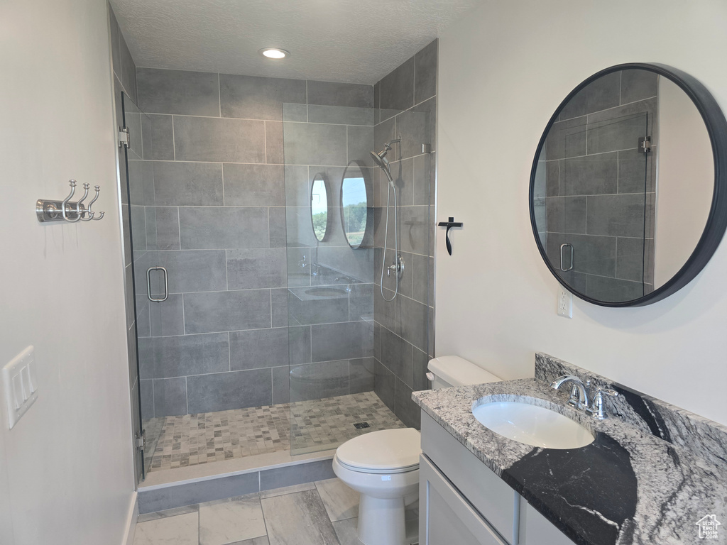 Bathroom with toilet, vanity, a shower stall, and recessed lighting