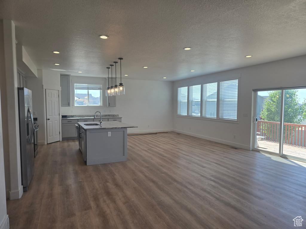 Kitchen featuring a sink, a center island with sink, recessed lighting, dark wood-style floors, and gray cabinets