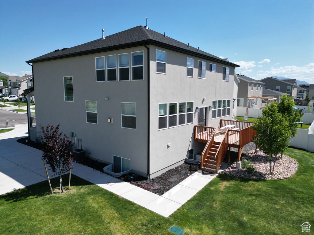 Back of house with a lawn, a wooden deck, stucco siding, and a residential view