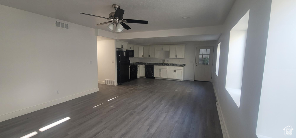 Unfurnished living room with baseboards, a ceiling fan, and dark wood-style flooring