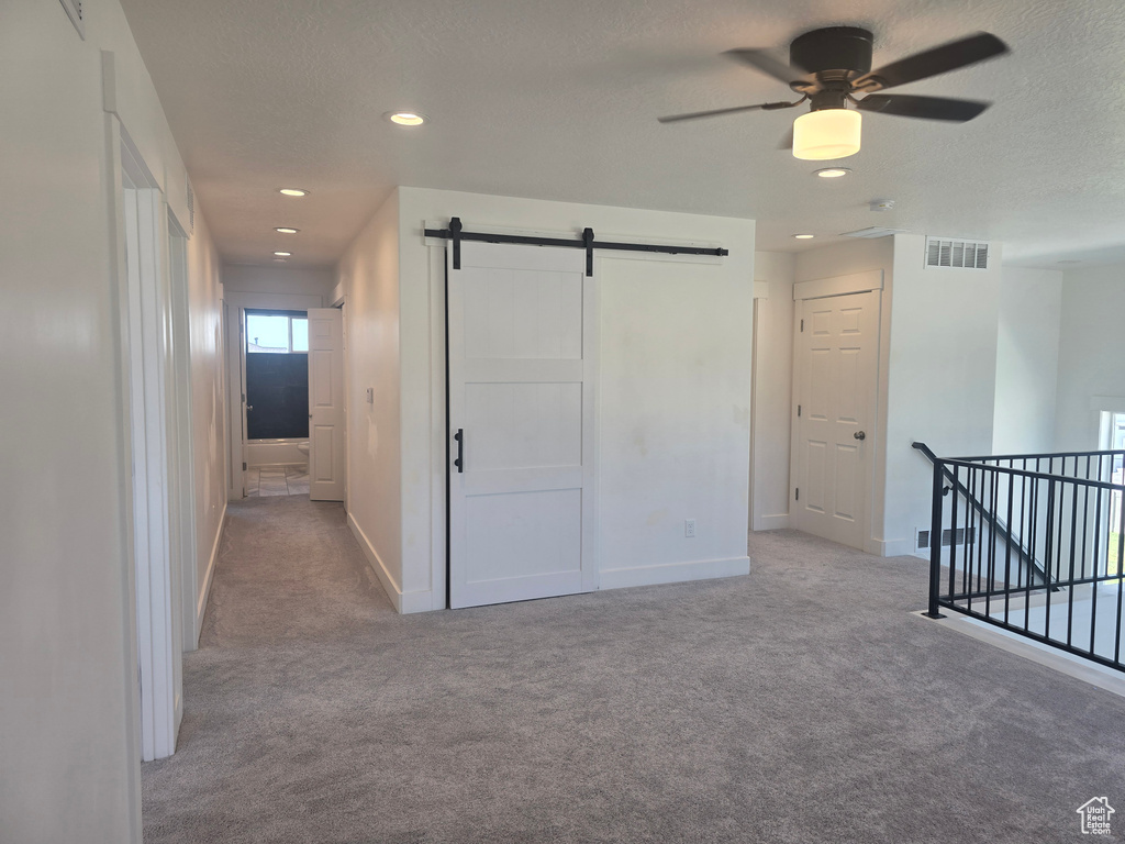 Hall featuring a barn door, carpet flooring, baseboards, recessed lighting, and an upstairs landing