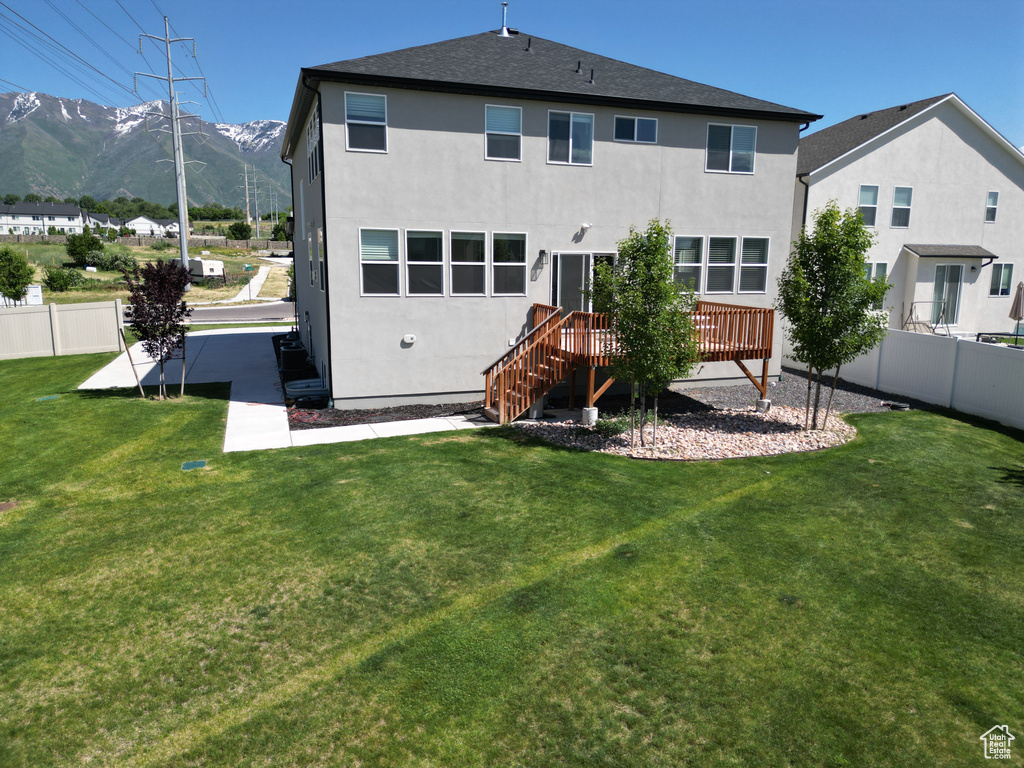 Rear view of house with stucco siding, a deck with mountain view, and stairway