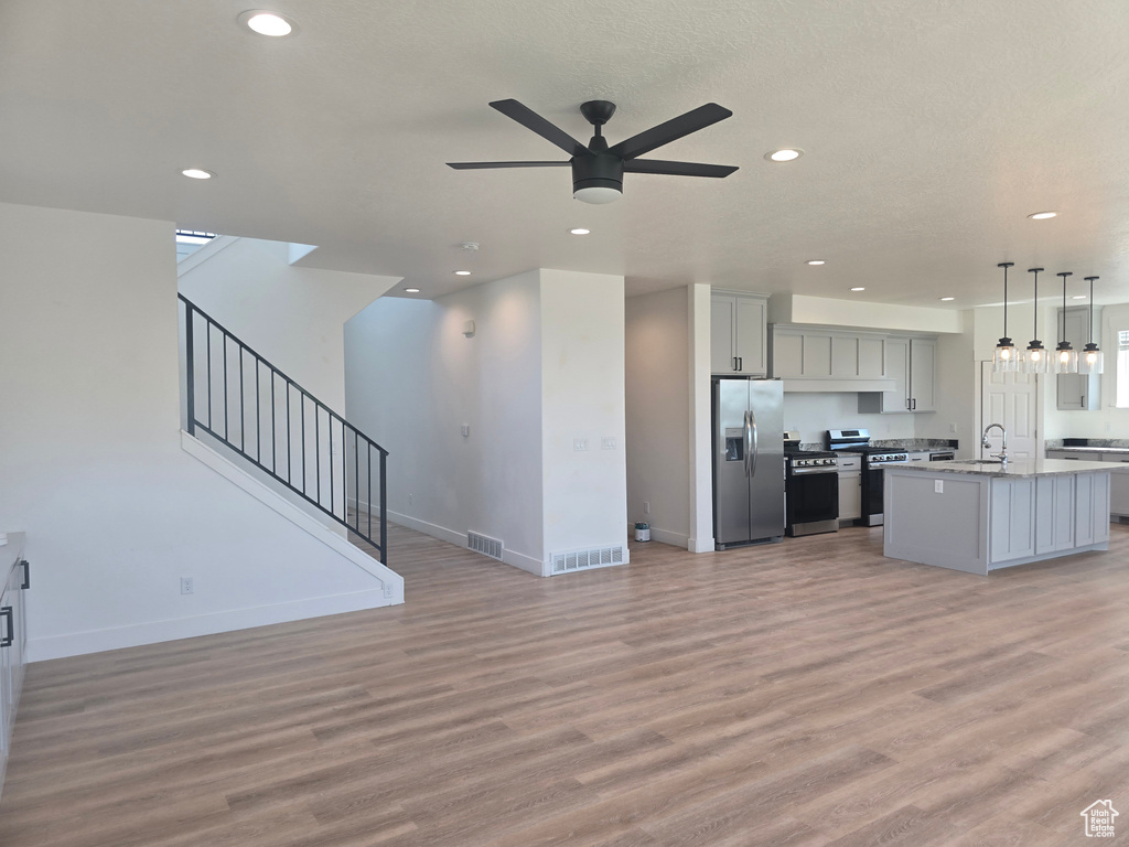 Unfurnished living room featuring light wood finished floors, recessed lighting, ceiling fan, and baseboards