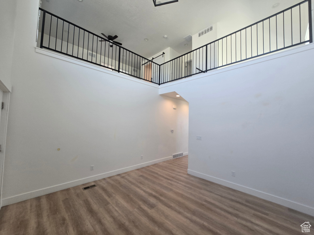 Unfurnished room with a towering ceiling, wood finished floors, baseboards, and stairway