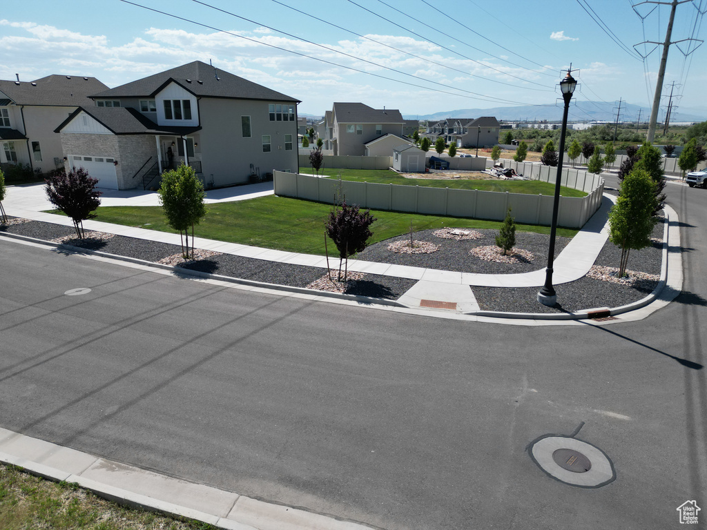 View of asphalt road with street lights, curbs, a residential view, and sidewalks