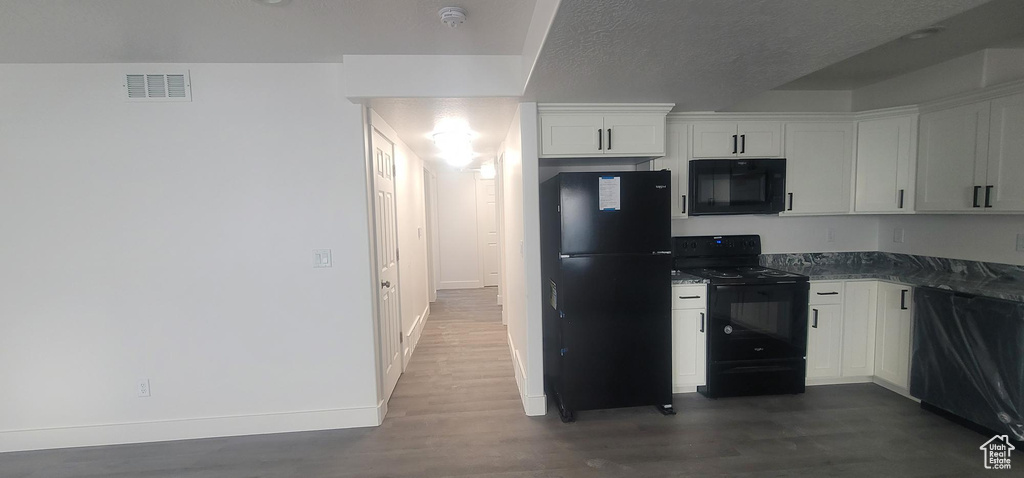 Kitchen featuring black appliances, dark wood finished floors, baseboards, white cabinetry, and dark countertops